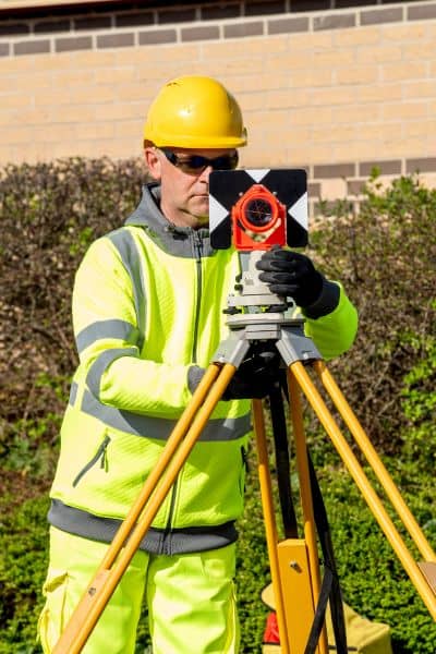 Field land survey equipment - ALTA SURVEY Mississippi Surveyor using field equipment during a property measurement, showing the traditional work behind an ALTA Land Title Survey