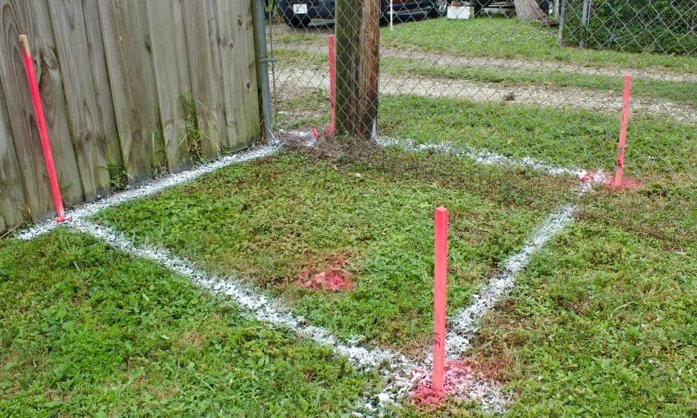 Boundary line survey showing property corners clearly marked with stakes and paint near a residential fence