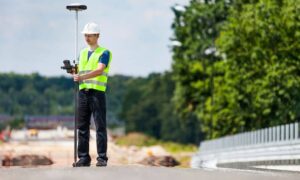Construction surveyor using GPS equipment to mark layout on an active road construction site