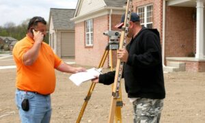 Surveyor measuring a home’s foundation height for a FEMA elevation certificate
