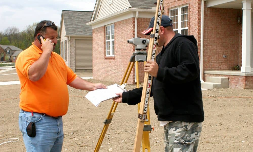 Surveyor measuring a home’s foundation height for a FEMA elevation certificate