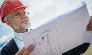 Engineer reviewing a land site plan outdoors as part of a due diligence survey for development projects